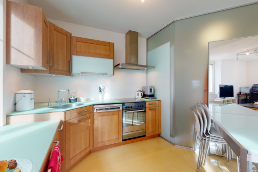 küche mit ofen, rauchextraktor, fernseher, hellem boden, braunen schränken und hellen arbeitsplatten