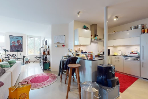 cuisine avec lumière naturelle, bar, hotte, plan de travail foncé, et sol clair