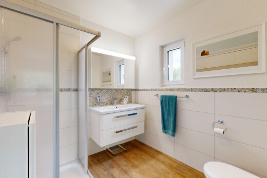 salle de bains avec douche, salle de bain complète, miroir, lavabo (ou coiffeuse selon le contexte), et mur en carrelage