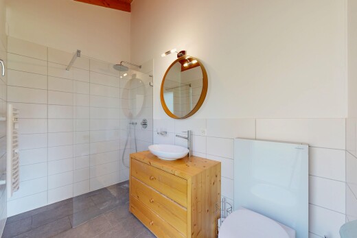 salle de bains avec salle de bain complète, miroir, lavabo (ou coiffeuse selon le contexte), douche, et mur en carrelage