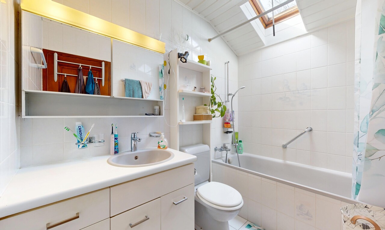salle de bains avec puits de lumière, lavabo (ou coiffeuse selon le contexte), miroir, toilette, et inside property