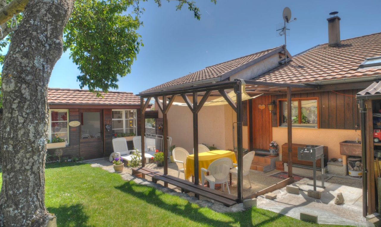façade avec property visible, toit en tuiles, bardage vertical, terrasse, et day time