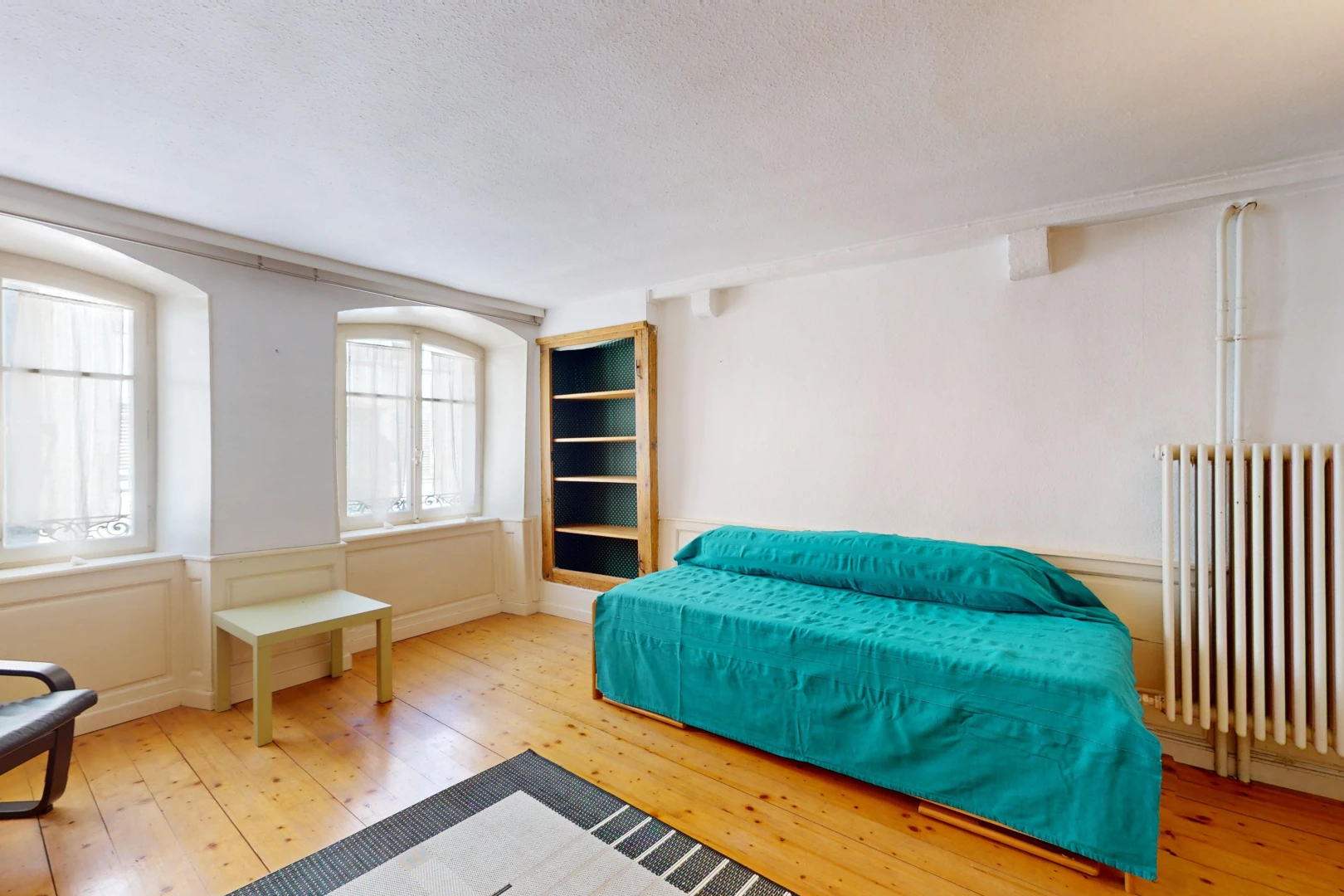 chambre avec plancher de bois, radiateur, et lumière naturelle