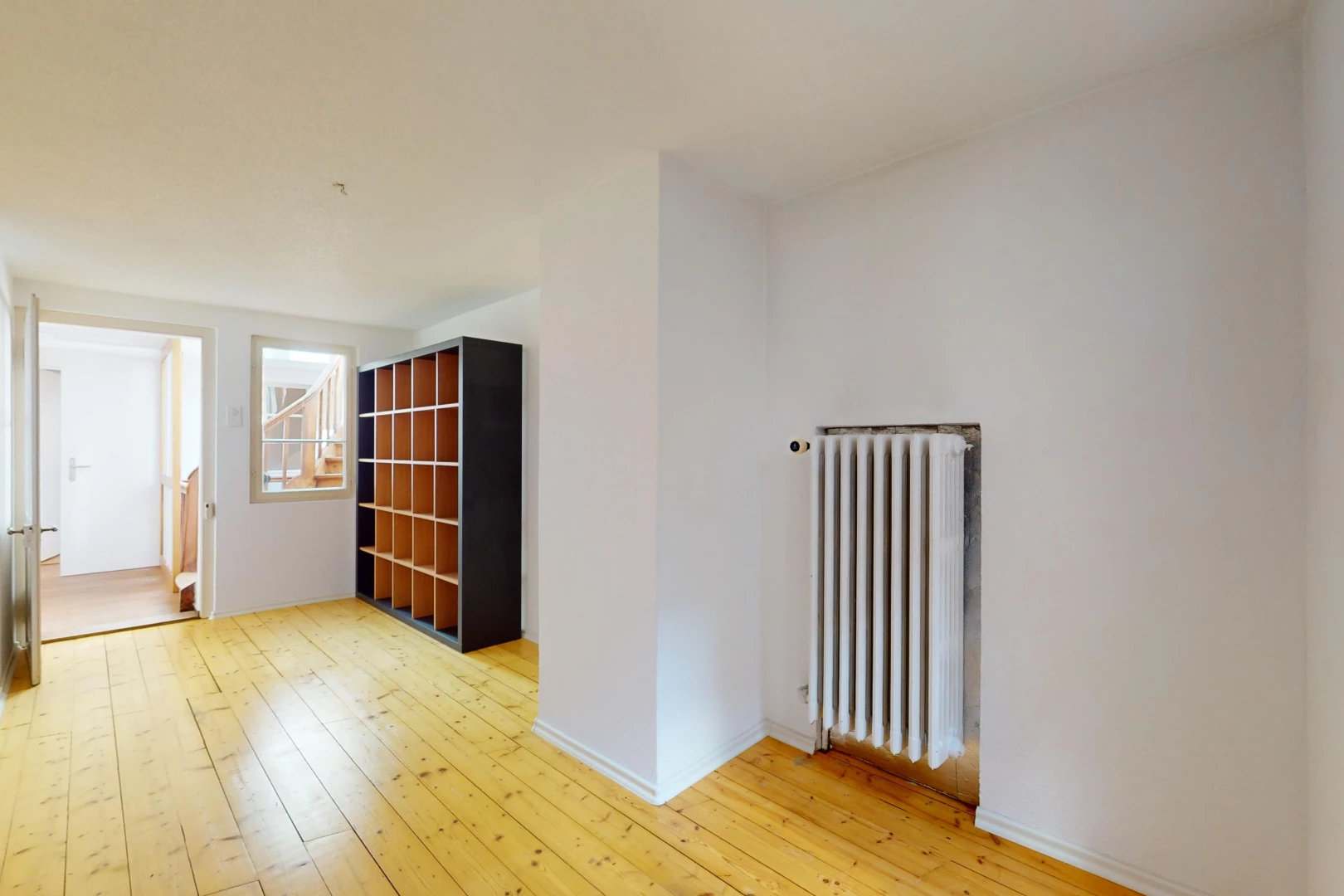 pièce vide avec plancher de bois, radiateur, et lumière naturelle