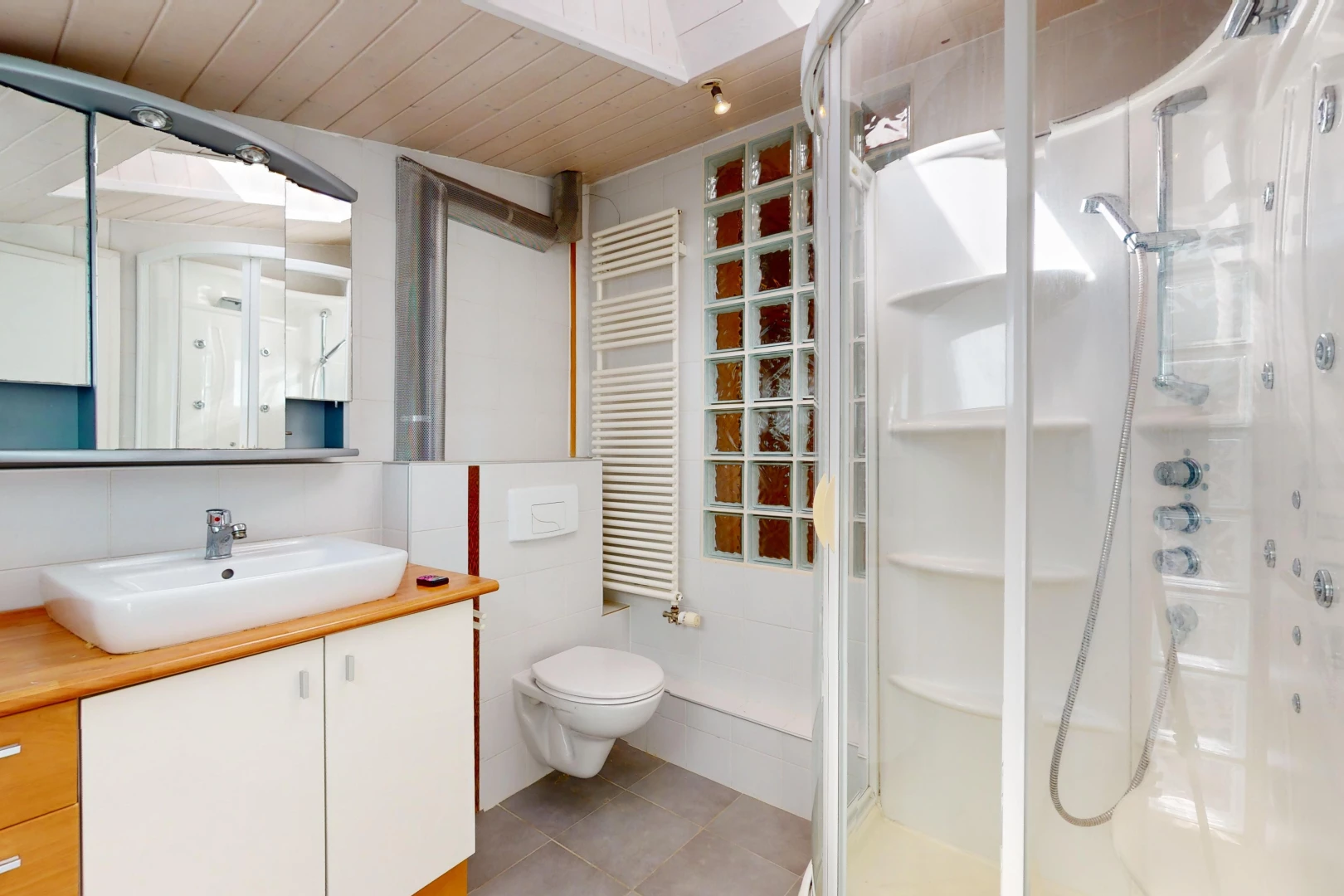 salle de bain avec plafond de bois, meuble-lavabo, miroir, toilettes, et radiateur