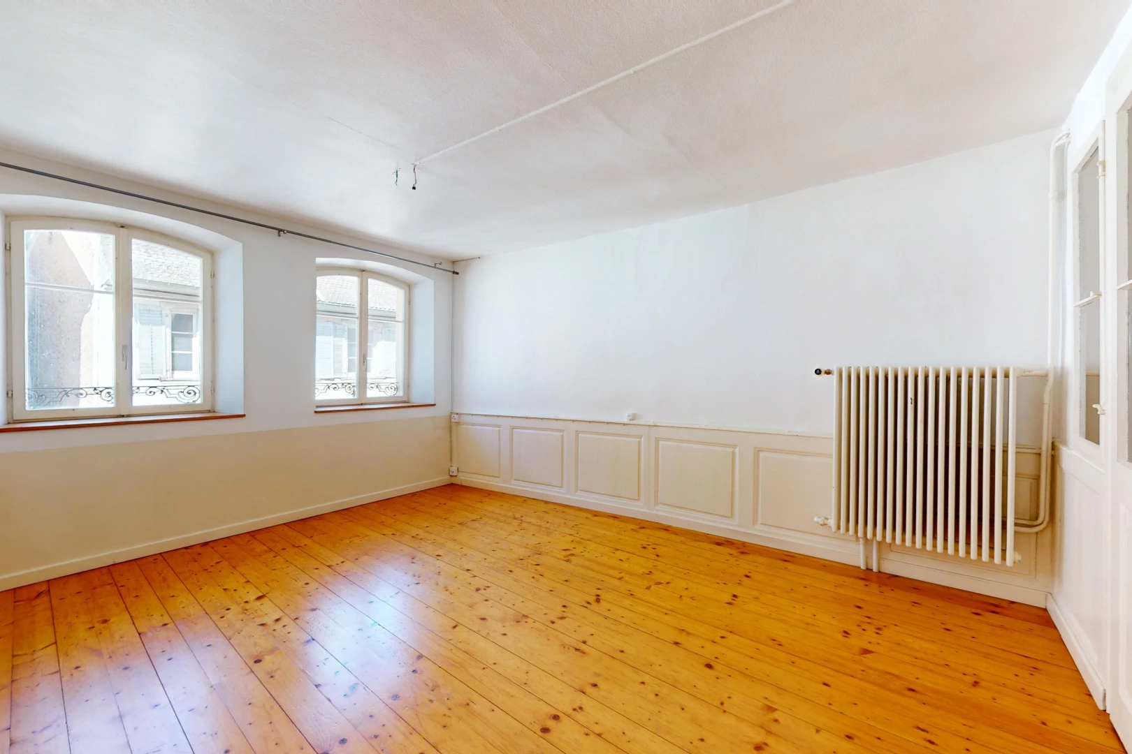 pièce vide avec plancher de bois, radiateur, et lumière naturelle