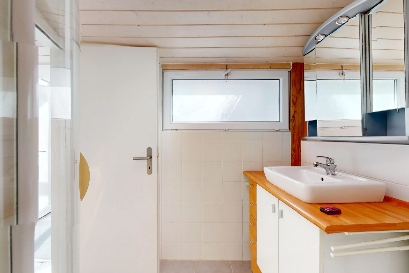 salle de bain avec meuble-lavabo, miroir, lumière naturelle, et vasque