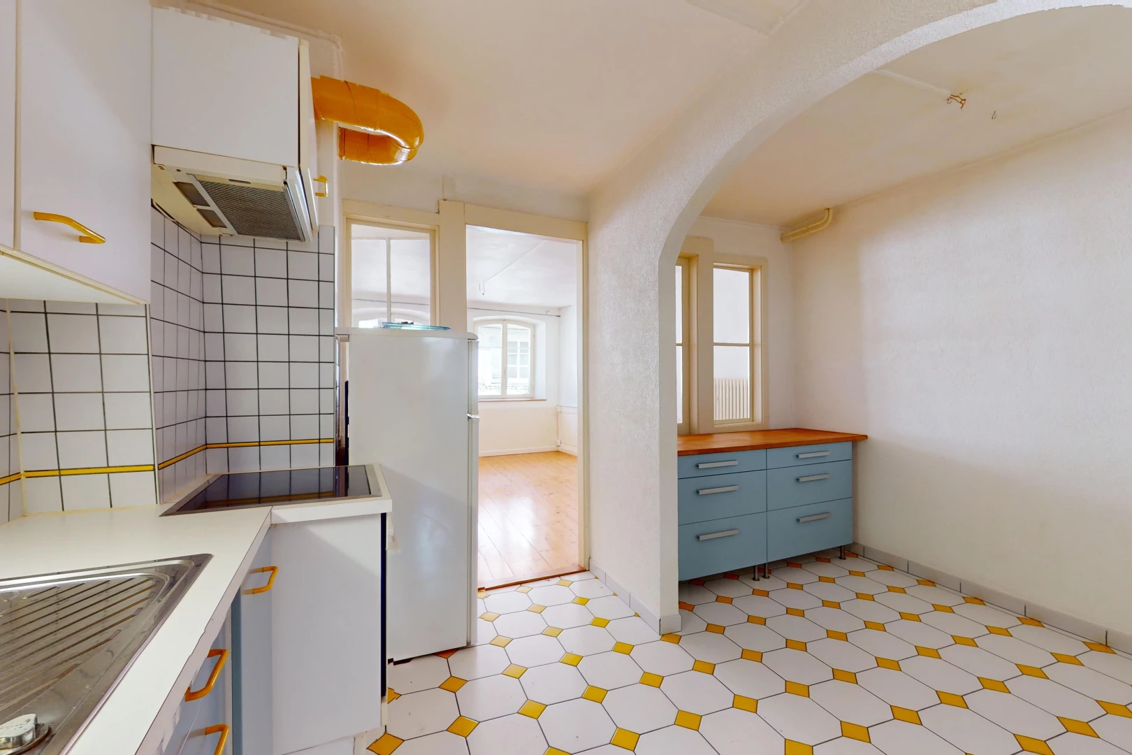 cuisine avec réfrigérateur, plancher de bois, carrelage, lumière naturelle, et hotte