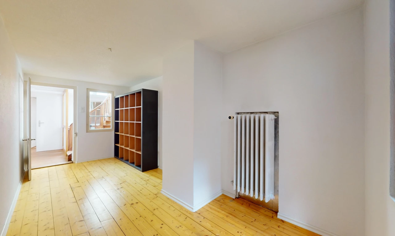 pièce vide avec plancher de bois, radiateur, et lumière naturelle