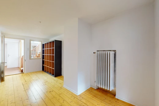 pièce vide avec plancher de bois, radiateur, et lumière naturelle
