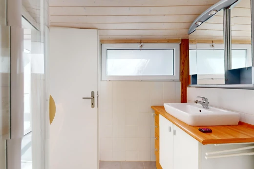 salle de bain avec meuble-lavabo, miroir, lumière naturelle, et vasque