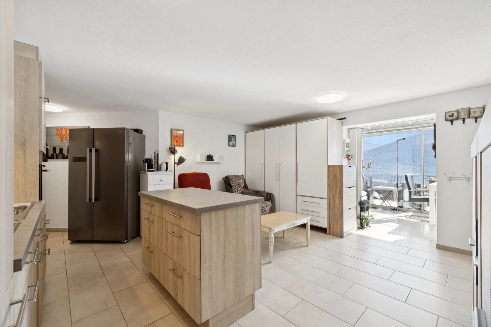 cuisine avec réfrigérateur, armoires marron clair, light brown cabinets, light floor, et îlot de cuisine