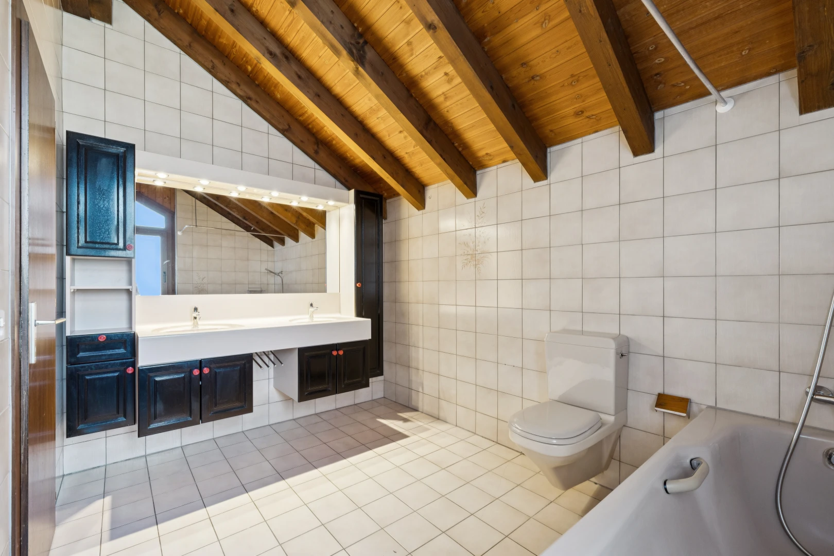 salle de bains avec mur en carrelage, tile wall, salle de bain complète, plafond à poutres, et beamed ceiling