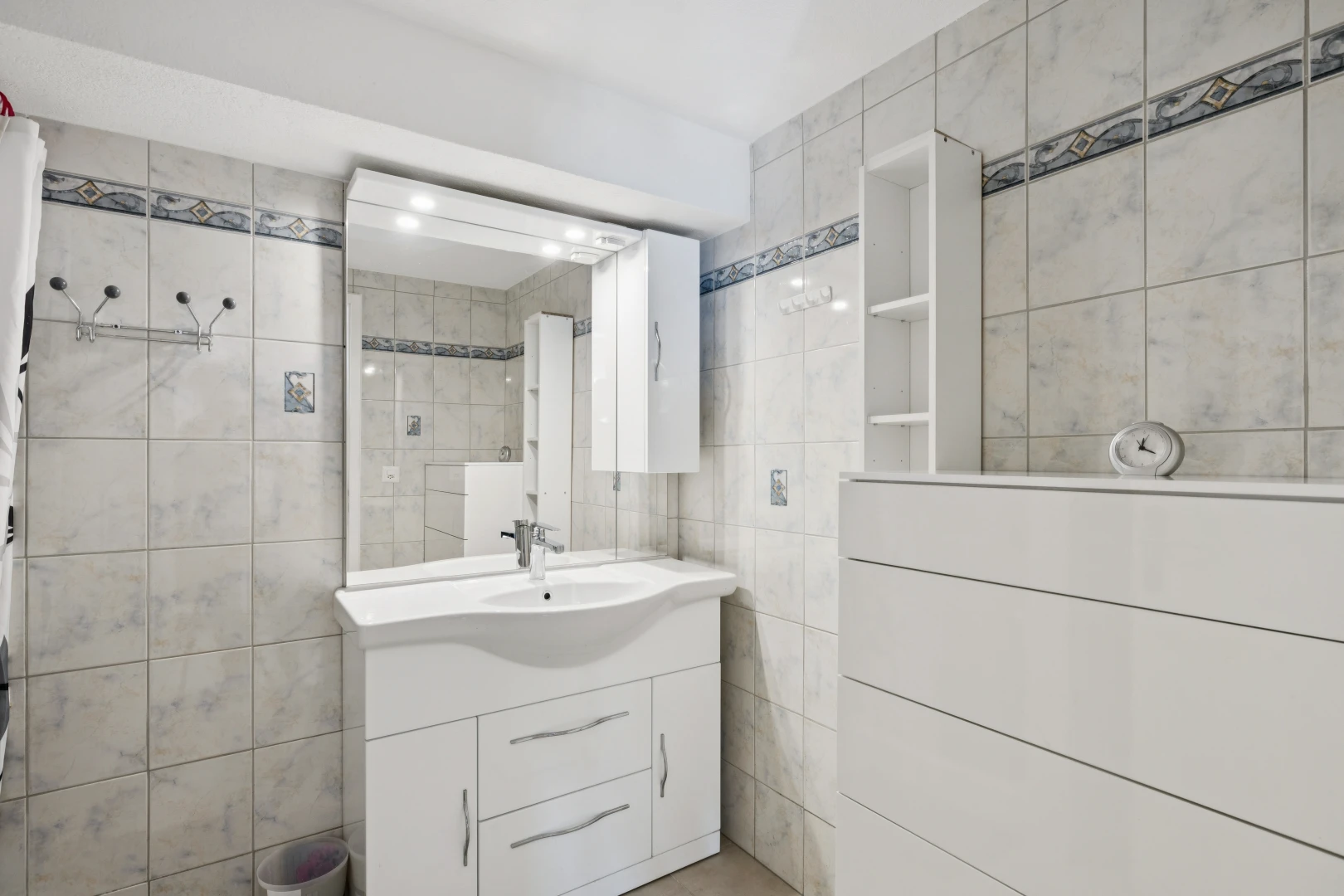 salle de bains avec miroir, mur en carrelage, tile wall, lavabo (ou coiffeuse selon le contexte), et inside property