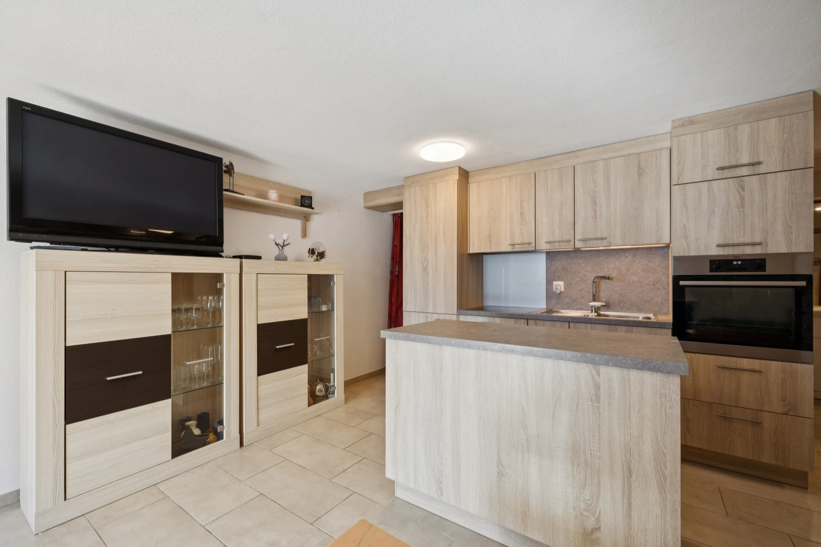 cuisine avec four, télévision, light floor, évier, et îlot de cuisine