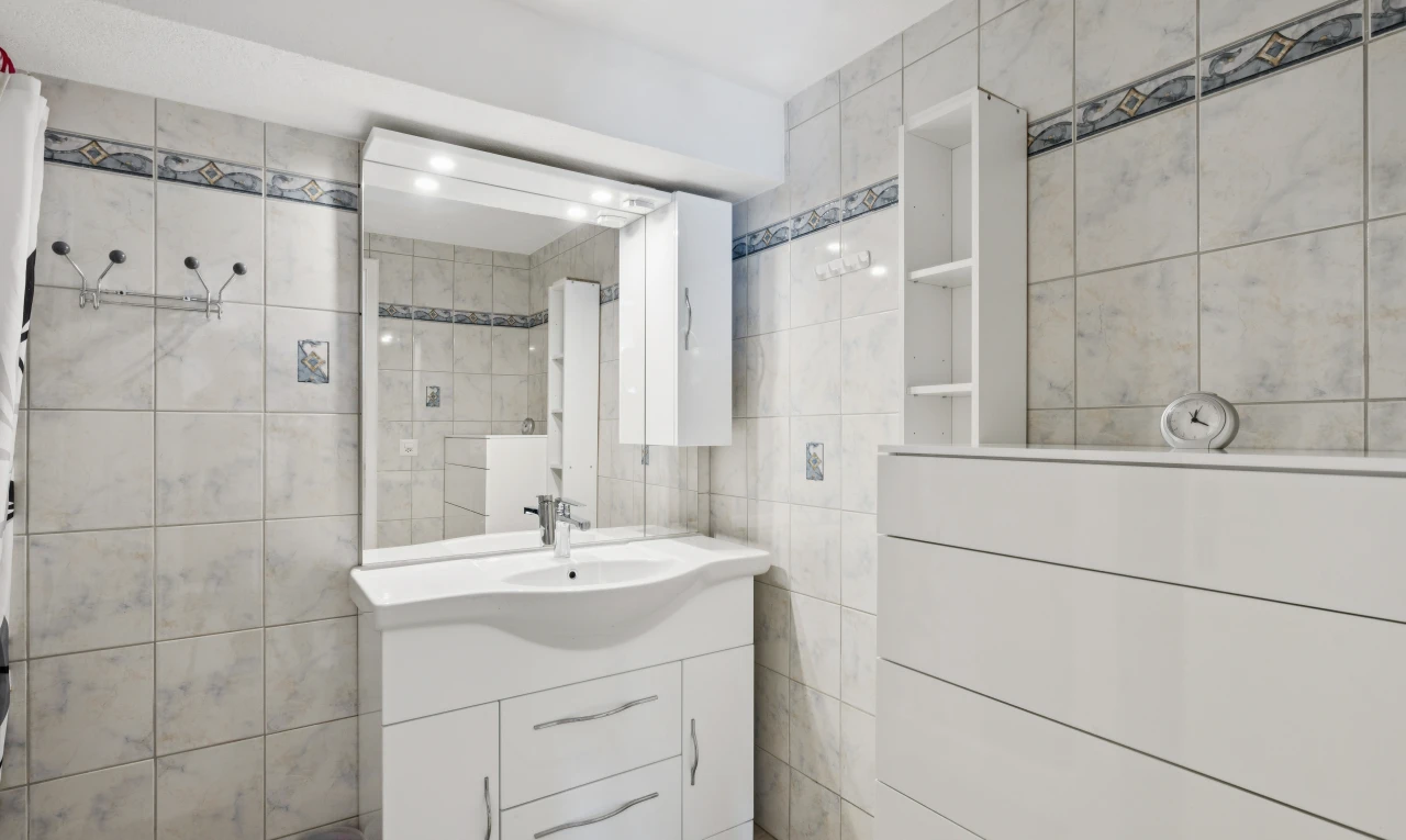 salle de bains avec miroir, mur en carrelage, tile wall, lavabo (ou coiffeuse selon le contexte), et inside property