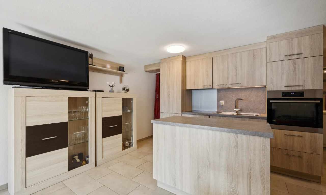 cuisine avec four, télévision, light floor, évier, et îlot de cuisine