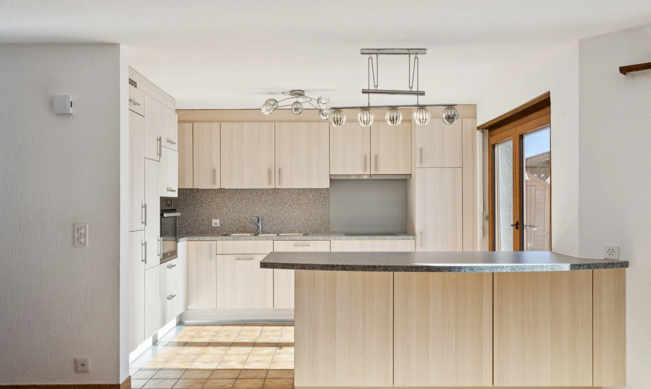 cuisine avec armoires marron clair, light brown cabinets, plans de travail, dark countertops, et light floor