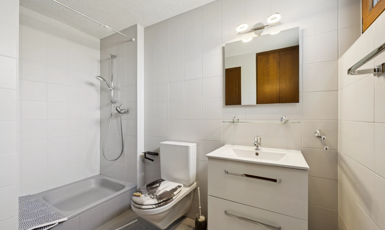 salle de bains avec mur en carrelage, tile wall, lavabo (ou coiffeuse selon le contexte), salle de bain complète, et miroir