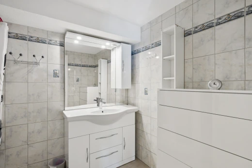 salle de bains avec miroir, mur en carrelage, tile wall, lavabo (ou coiffeuse selon le contexte), et inside property