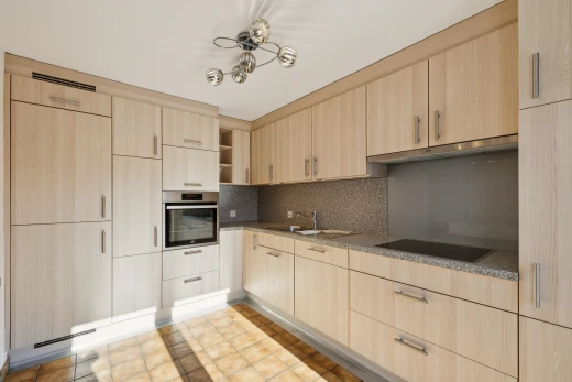 cuisine avec four, armoires marron clair, light brown cabinets, étagères ouvertes, et open shelves