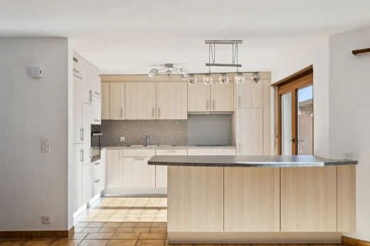 cuisine avec armoires marron clair, light brown cabinets, plans de travail, dark countertops, et light floor