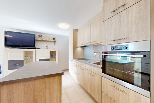 kitchen with stainless steel oven, light wood finish cabinets, light tile patterned flooring, and black electric cooktop