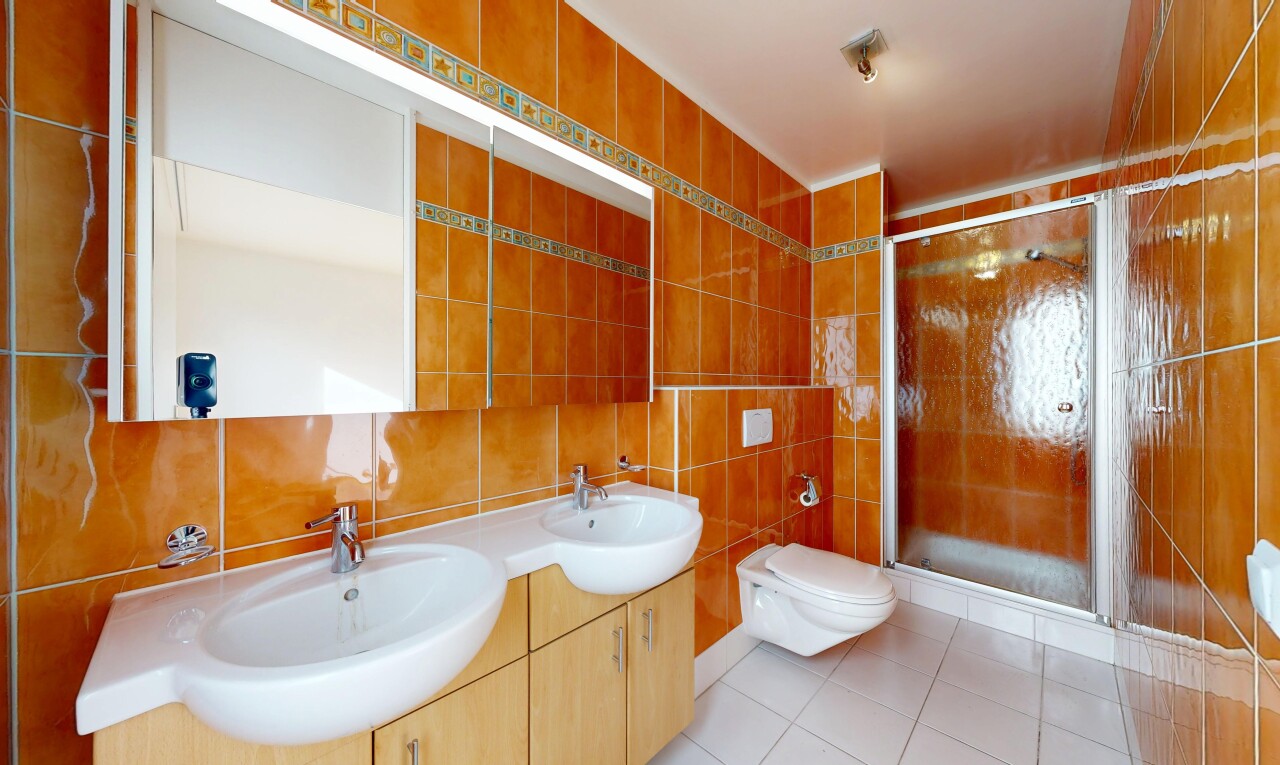full bathroom featuring tile walls, a shower stall, double vanity, and light tile patterned floors