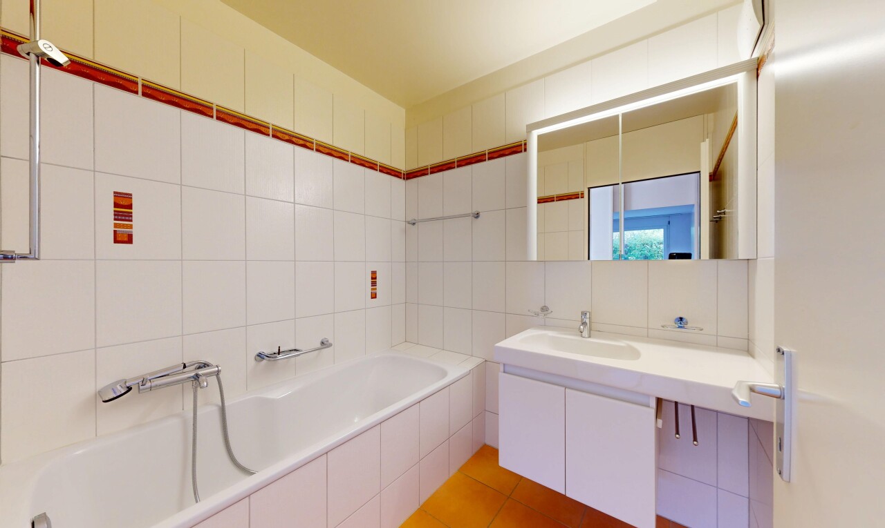full bath featuring a garden tub, tile walls, vanity, and light tile patterned floors