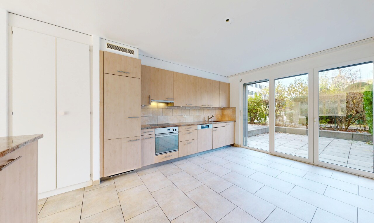 kitchen with light wood finish cabinets, oven, backsplash, and light countertops