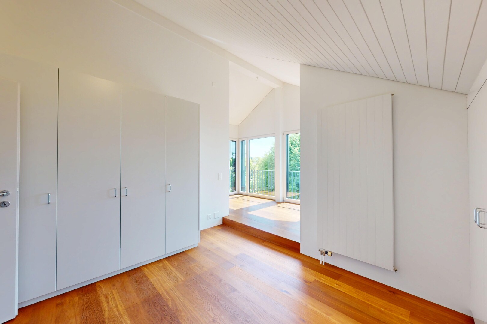 pièce vide avec wood finish floor, sol en finition bois, natural light, lumière naturelle, et vaulted ceiling