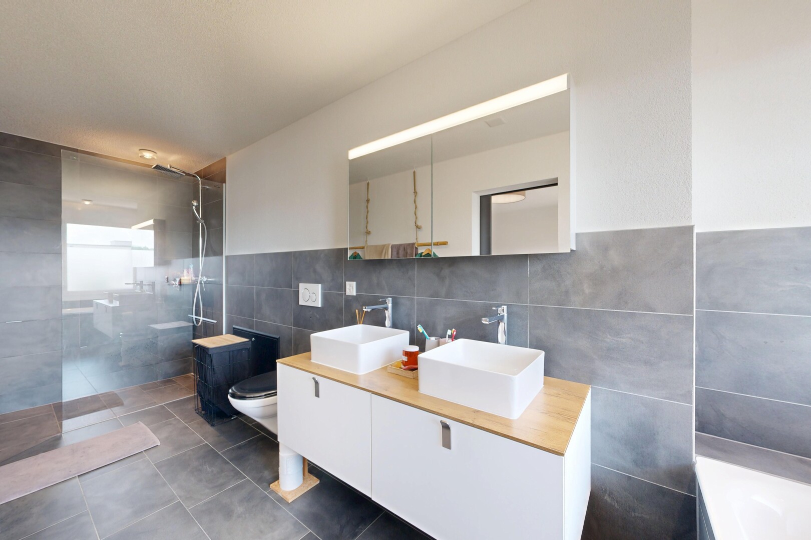 salle de bains avec mur en carrelage, tile wall, salle de bain complète, douche, et double vasque