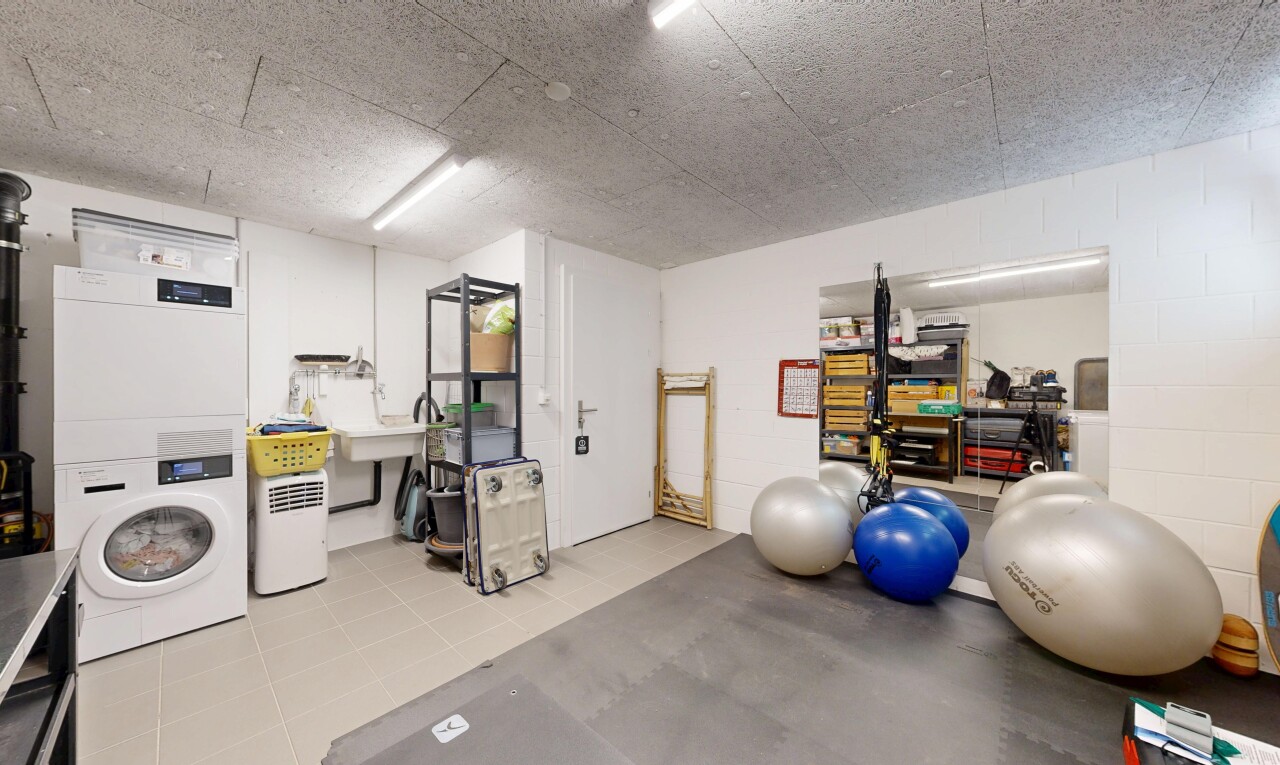 gym avec inside property, lave-linge et sèche-linge superposés, mur en blocs de béton, concrete block wall, et light floor