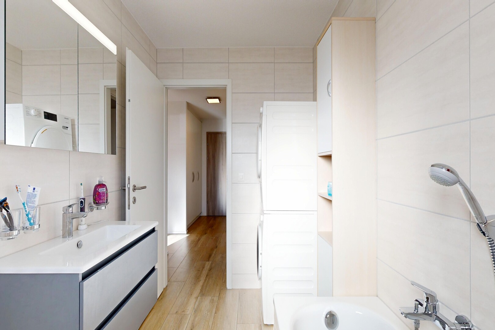 full bathroom with vanity, washer / clothes dryer, light wood-type flooring, shower / bathtub combination, and tile walls