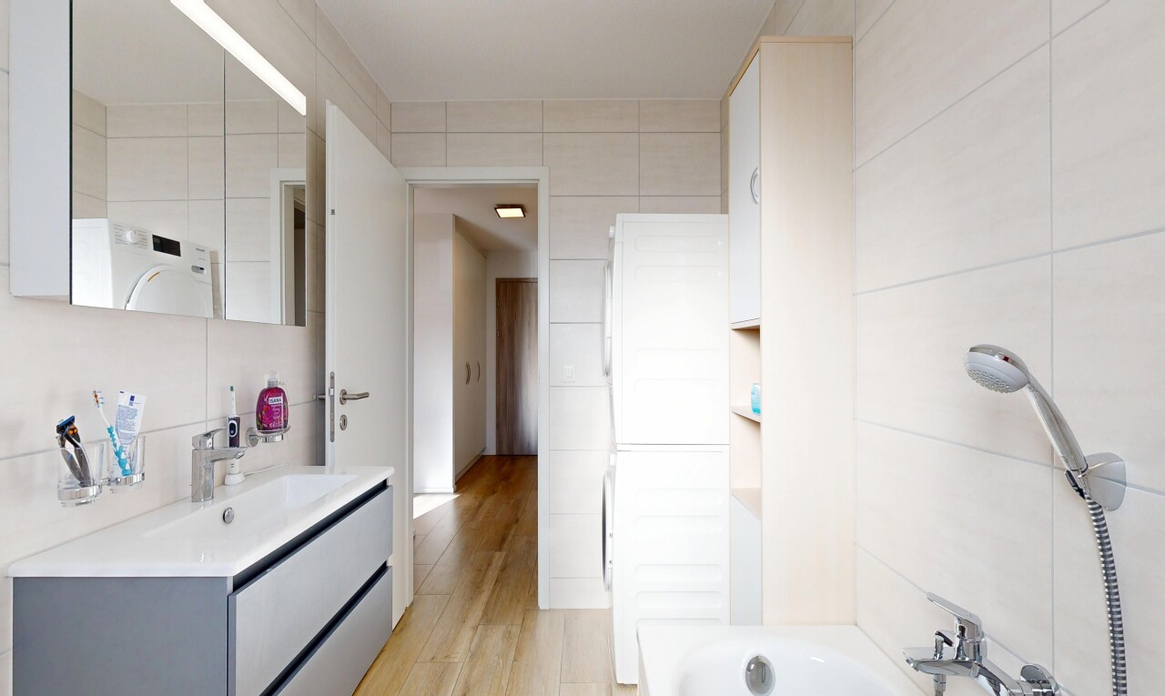 full bathroom with vanity, washer / clothes dryer, light wood-type flooring, shower / bathtub combination, and tile walls