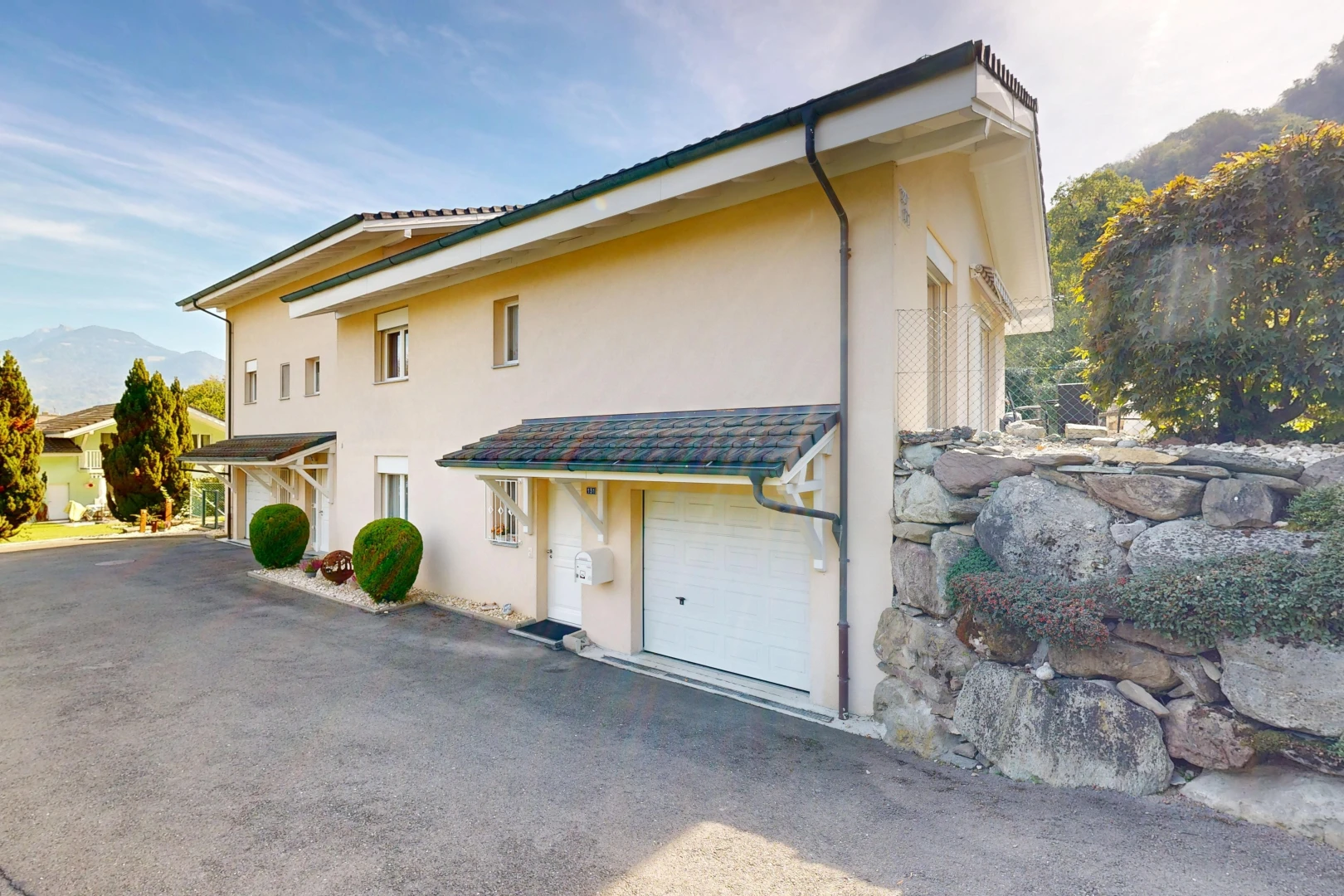 außenansicht mit eingebaute garage, property visible, stuckverkleidung, und day time