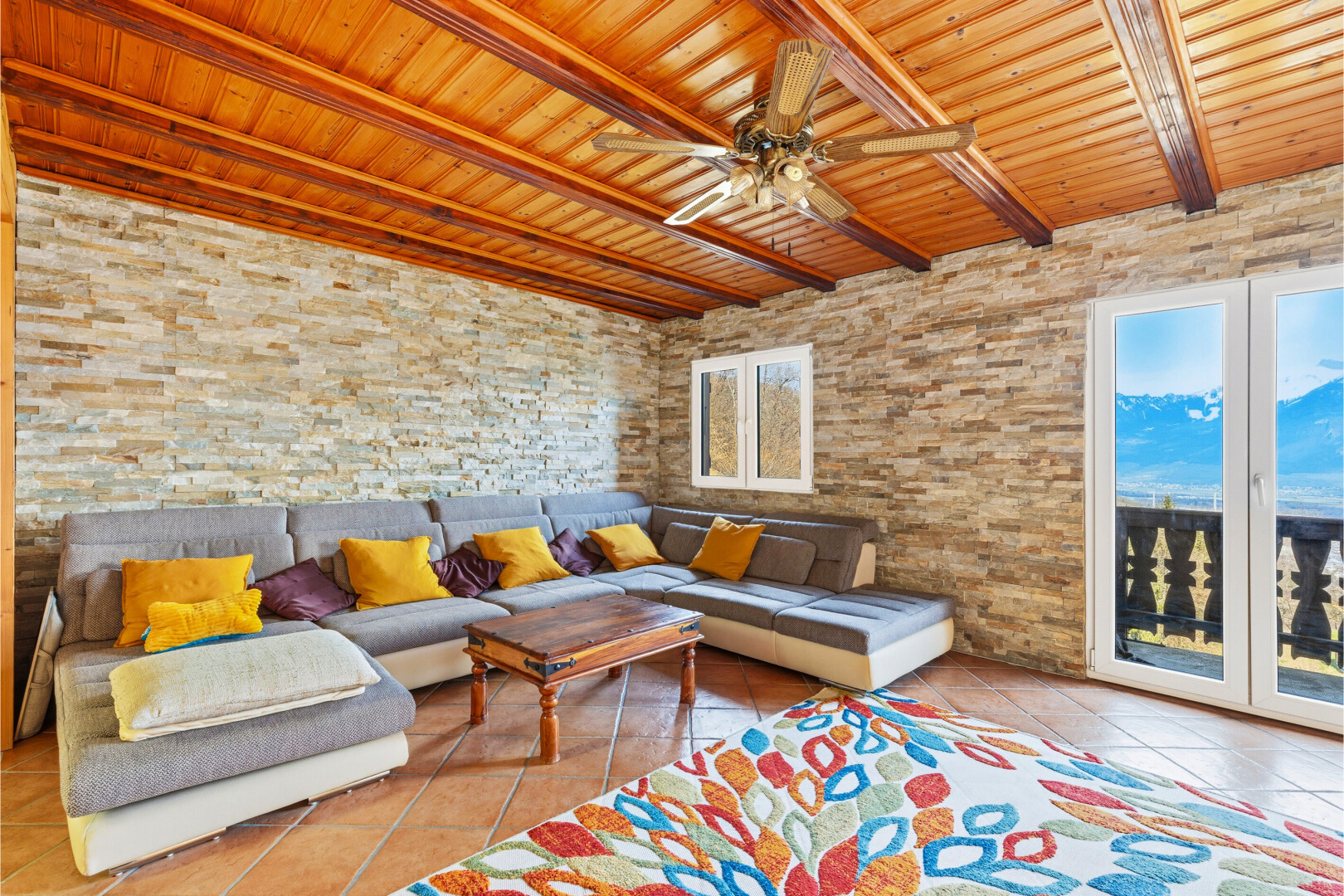 wohnzimmer mit beamed ceiling, balkendecke, tile floor, fliesenboden, und stone wall