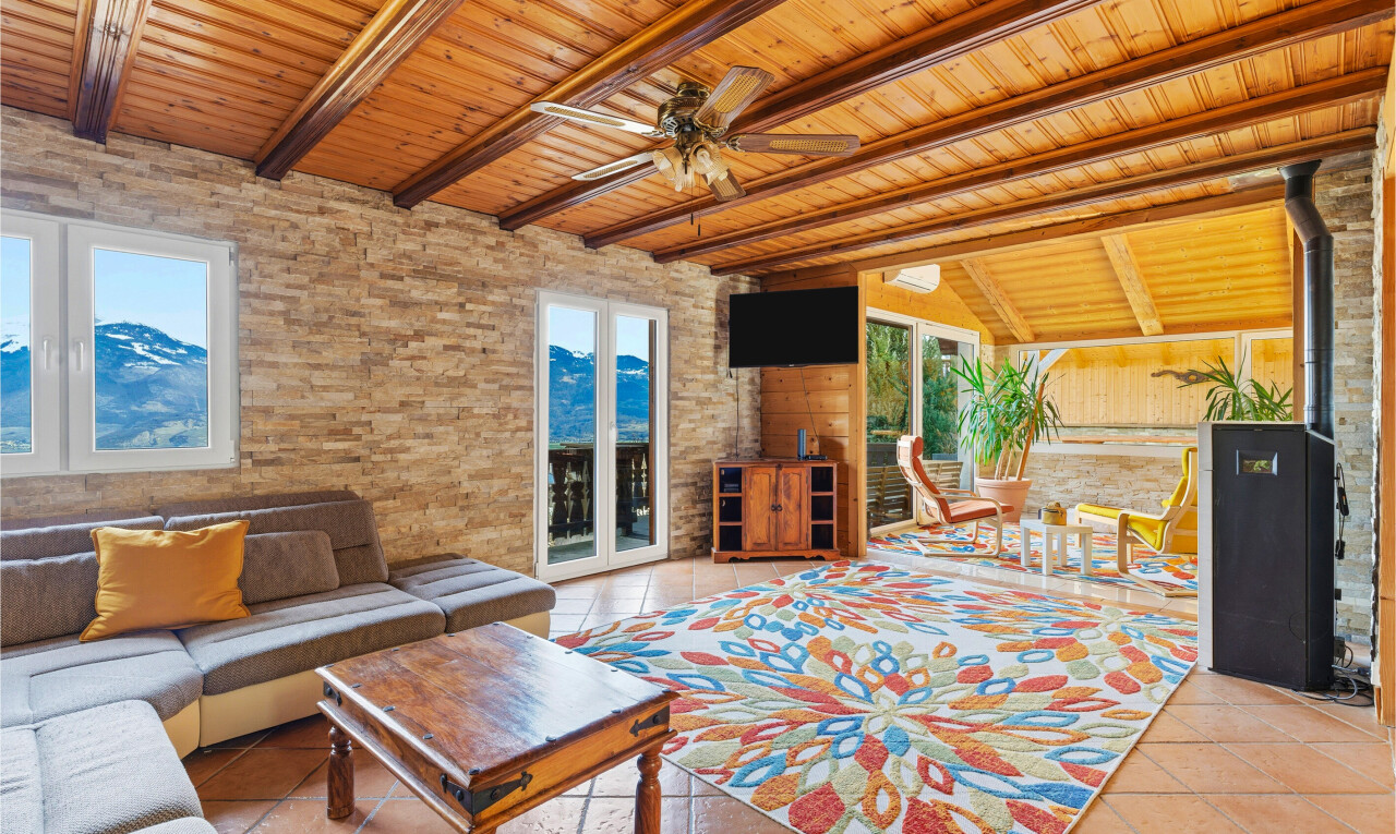 living room with a ceiling fan, plenty of natural light, wood ceiling, a wood stove, and light tile patterned floors