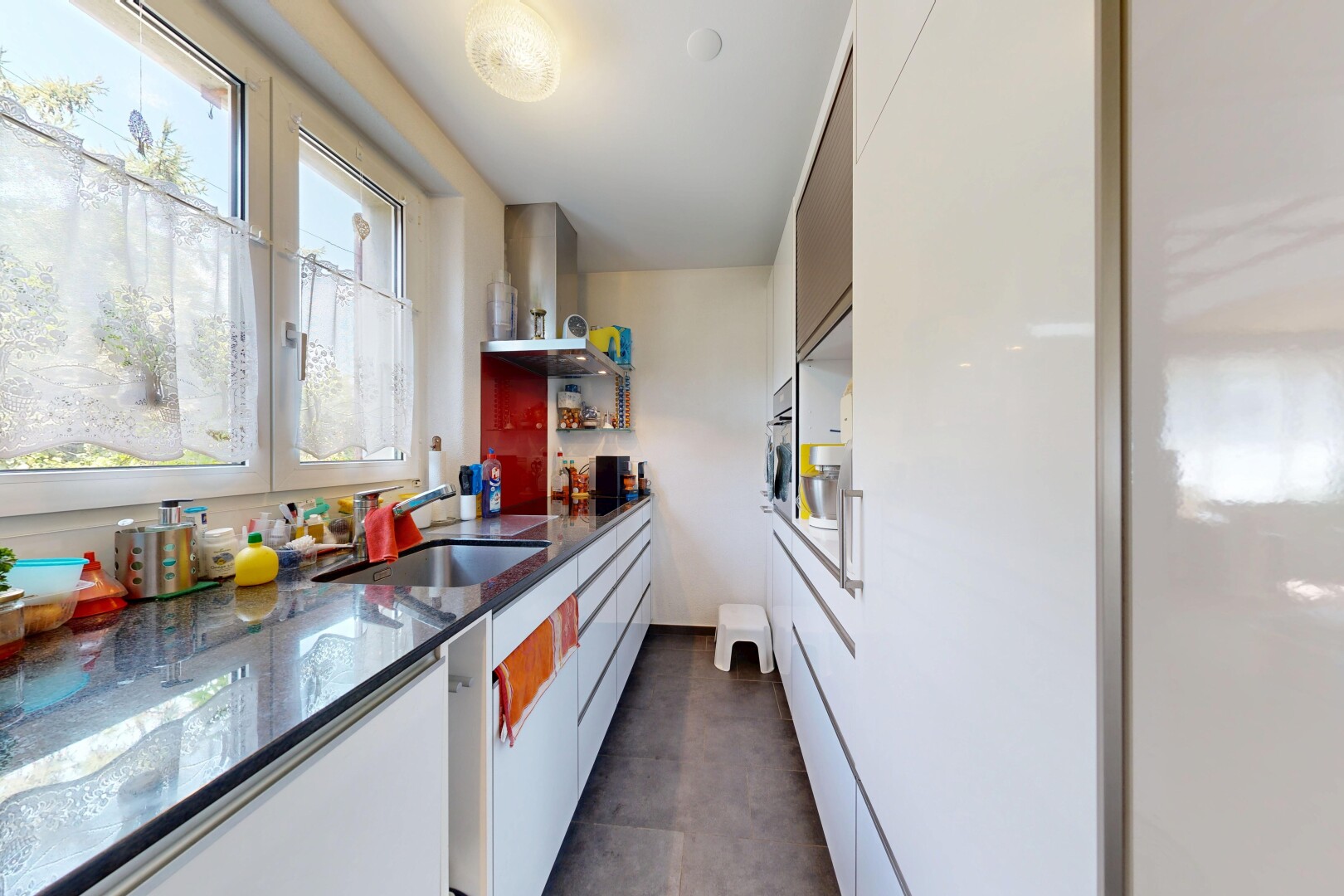 küche mit dark floor, flat panel cabinets, schränke mit flachen paneelen, dunstabzugshaube, und stone countertops