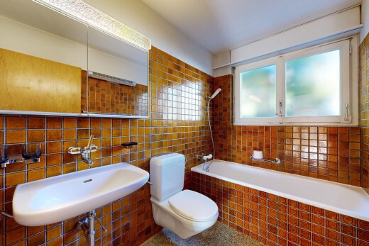 salle de bains avec toilette, miroir, évier, mur en carrelage, et tile wall