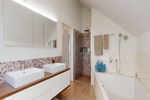 bathroom featuring walk in shower, lofted ceiling, a bath, double vanity, and light wood-style flooring
