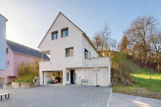 façade avec property visible, bardage en stuc, garage intégré, allée, et terrasse