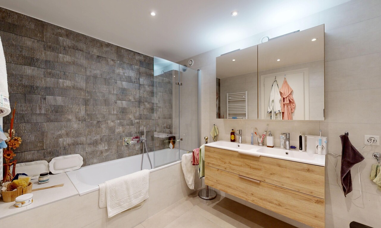 salle de bains avec salle de bain complète, double vasque, tile wall, mur en carrelage, et douche-bain combinés
