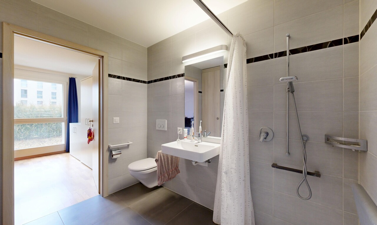 full bathroom with tiled shower and tile walls