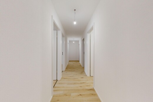 couloir avec éclairage suspendu, light floor, wood finish floor, sol en finition bois, et drywall