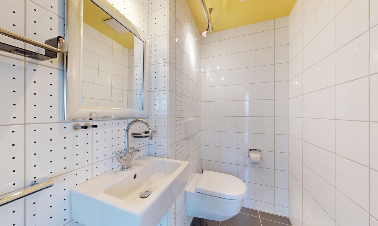 salle de bains avec toilette, tile wall, mur en carrelage, inside property, et miroir