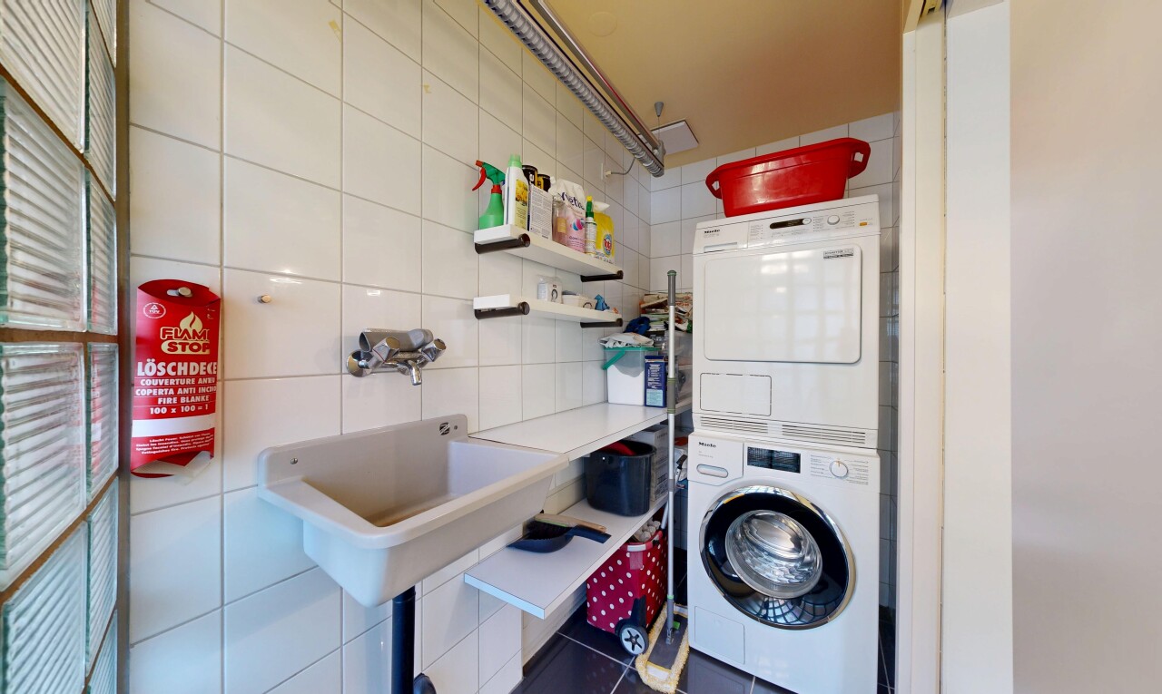buanderie avec lave-linge et sèche-linge superposés, buanderie, mur en carrelage, tile wall, et inside property