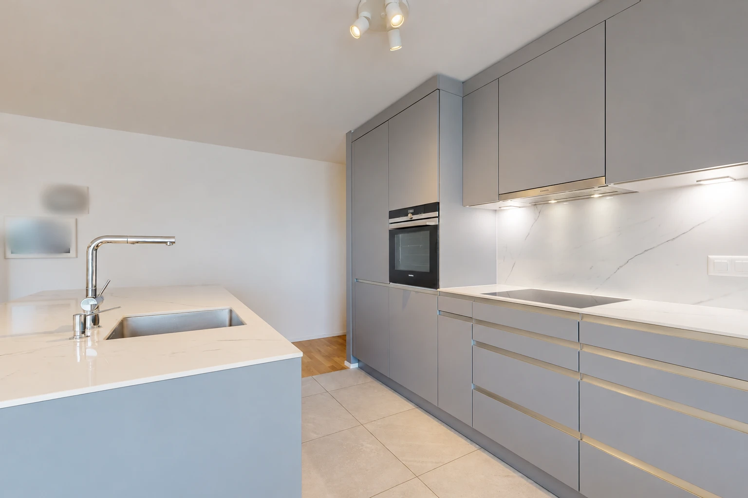 cuisine avec light countertops, light floor, four, évier, et armoires grises