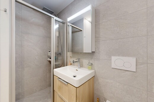 bathroom with a stall shower, vanity, and tile walls