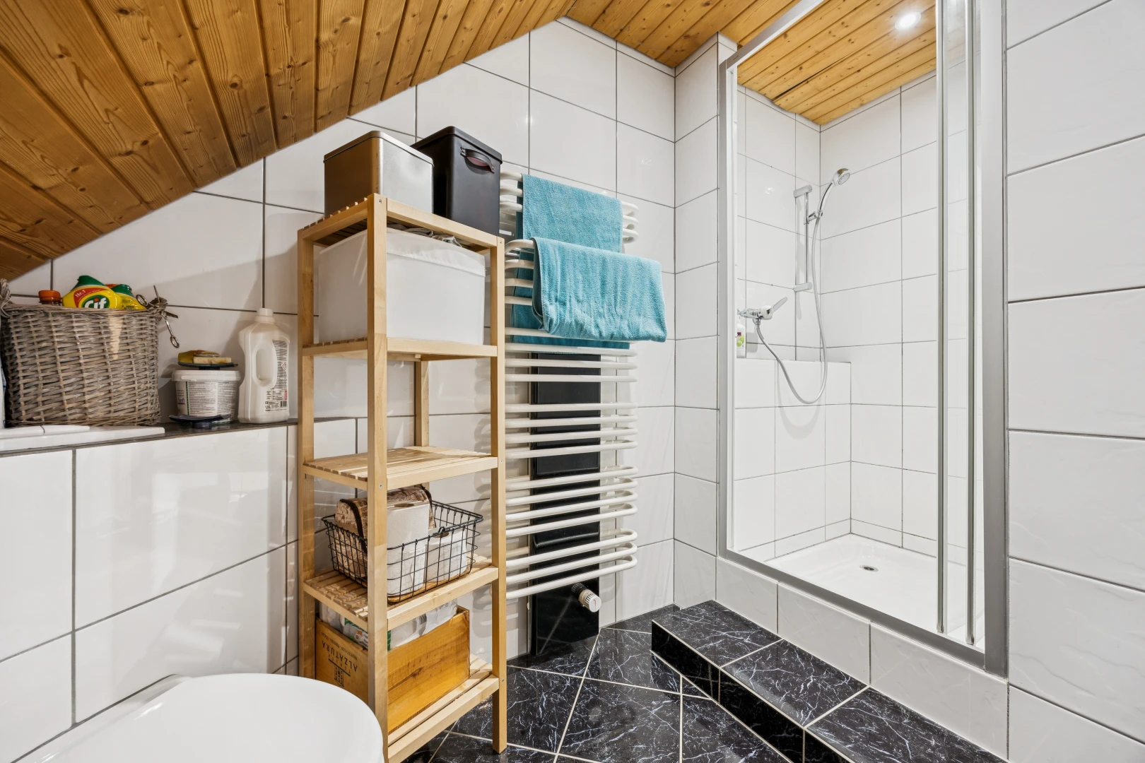 bathroom with a towel warming rack, a tile shower, and a vaulted wood ceiling
